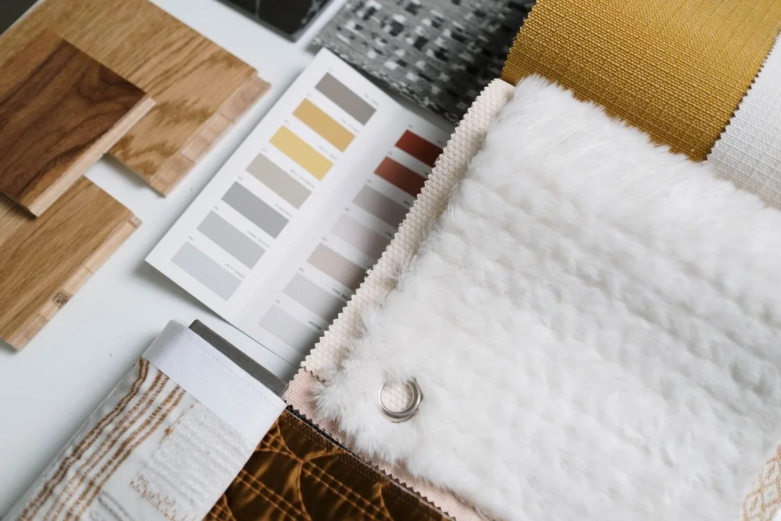 Neutral materials and colour swatches Wood samples, neutral color swatches and textured fabrics arranged on a table.
